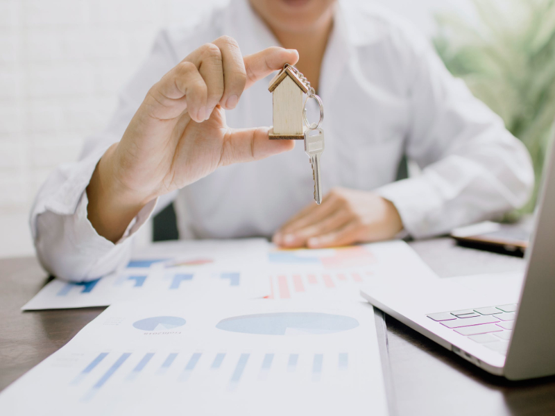 A man holding a miniature of house and a key