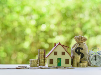 miniature house beside dollar bag and coins